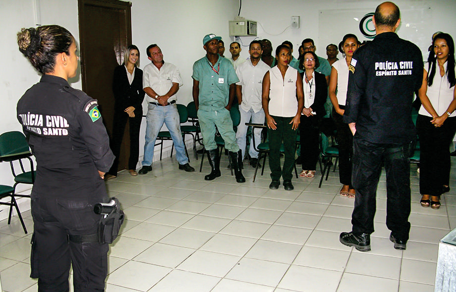 Foto de homens e mulheres escutando a dois policiais civis em campanha contra as drogas, ação de responsabilidade social Corpus.