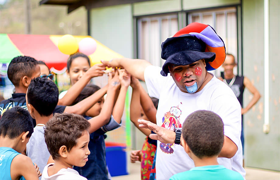 Homem com rosto pintado de palhaço ?brincando com crianças em ação de responsabilidade social Corpus do Dia das Crianças